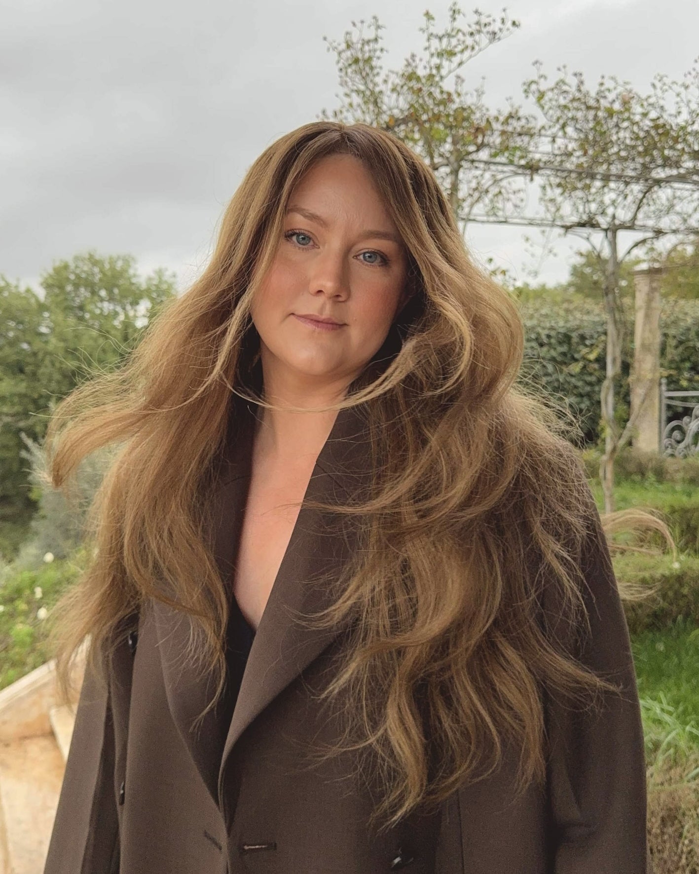 Woman wearing a long BHBD Elena wig with blended balayage, soft caramel brown tones and cool medium brown lengths.